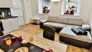 A modern apartment with a kitchenette, a sofa, a dining table with breakfast, and a view of the street. - Inviting Apartment in Inzing With Garden (Inzing)