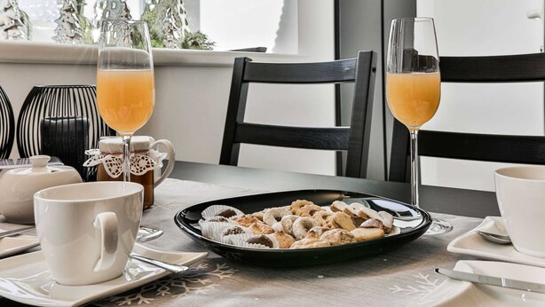 Ein Frühstückstisch mit Gebäck, zwei Orangensaftgläsern und einer Teekanne.