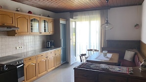 Cozinha com armários de madeira, fogão e área de refeições com mesa e cadeiras.