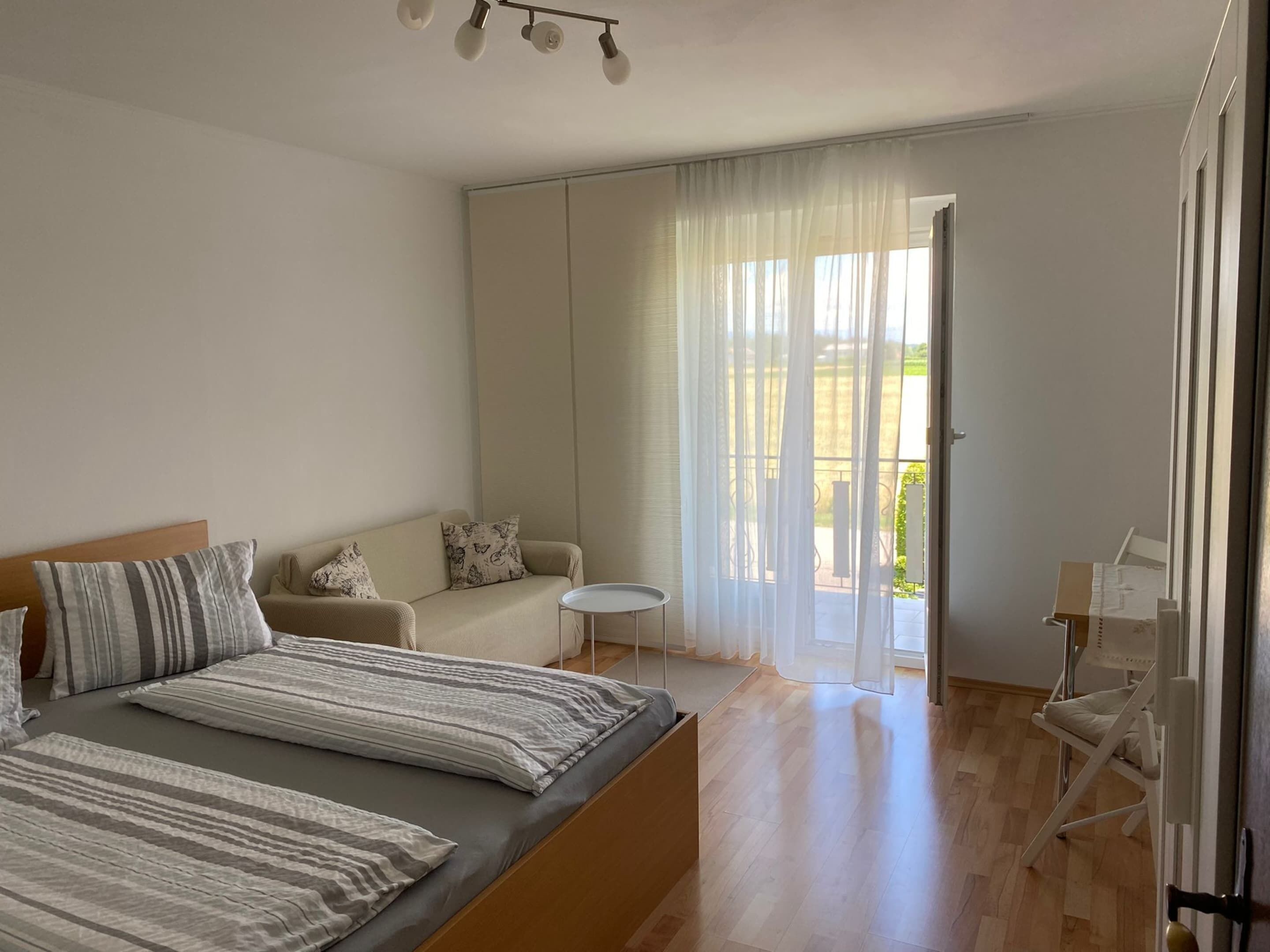 Une chambre moderne avec un grand lit, un canapé, une petite table et un balcon avec vue.