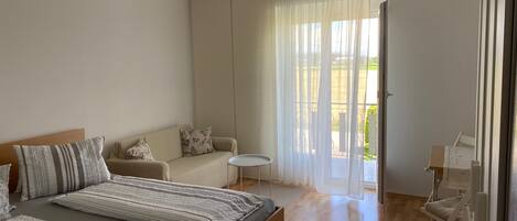 Une chambre moderne avec un grand lit, un canapé, une petite table et un balcon avec vue.