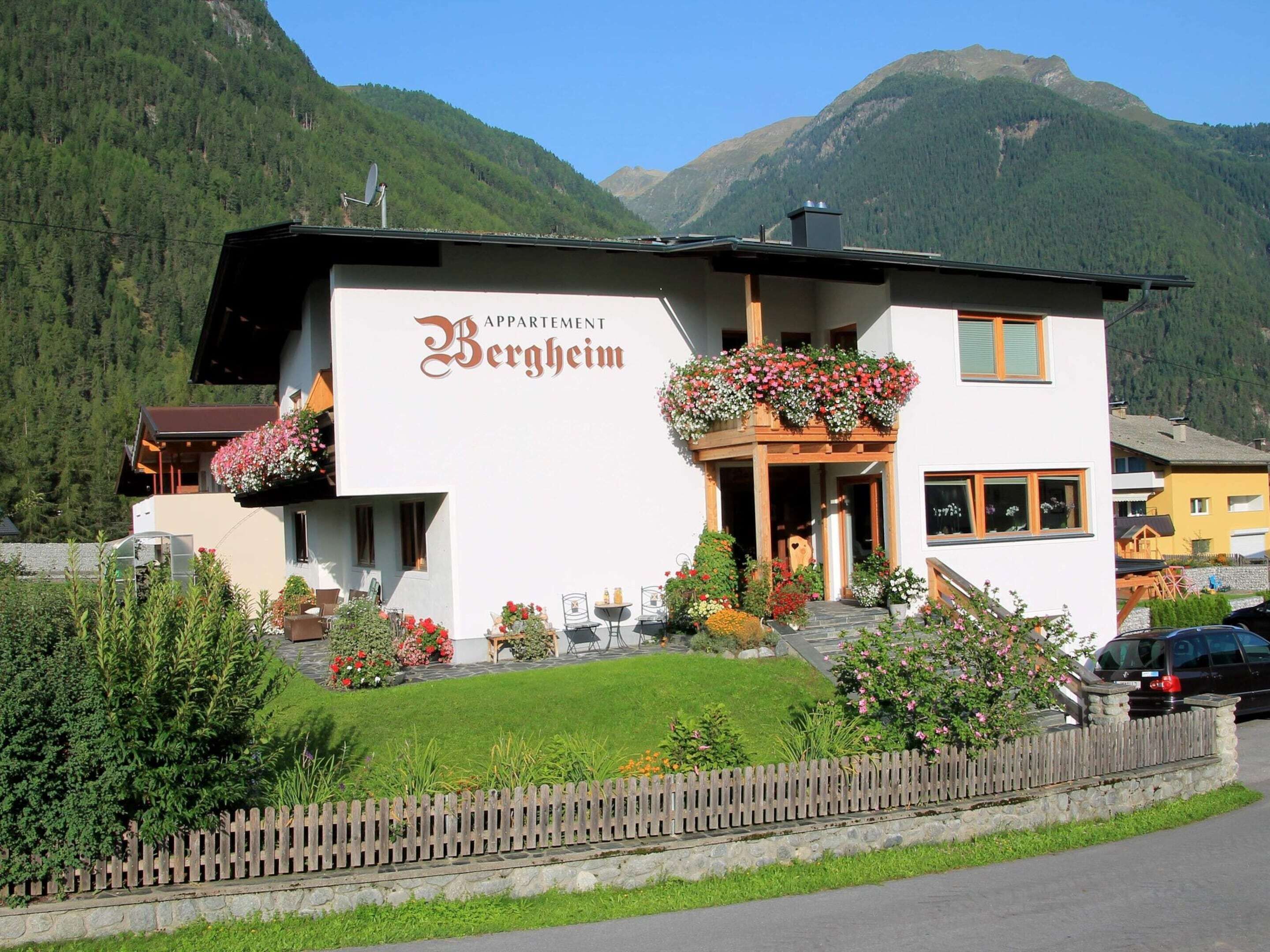 Valkoinen rakennus, jossa on kyltti, jossa lukee ”Appartement Bergheim”, ja parveke, jossa on kukkia.