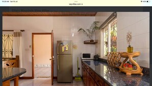 A kitchen with a refrigerator, microwave, and wooden cabinet.