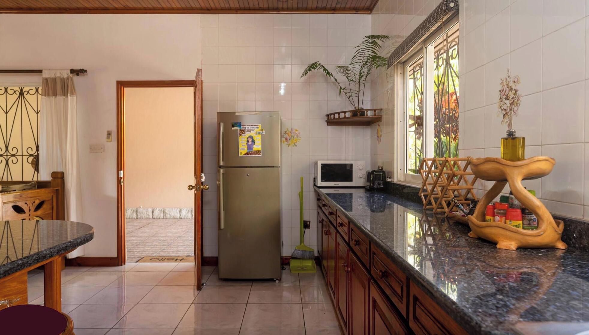 A kitchen with a refrigerator, microwave, and wooden cabinet.