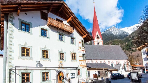 A traditional European building with a red-roofed tower, a balcony, and a sign reading "Hotel St. Georg".