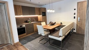 Una cocina moderna con armarios de madera, una mesa de comedor con sillas blancas y un horno empotrado.