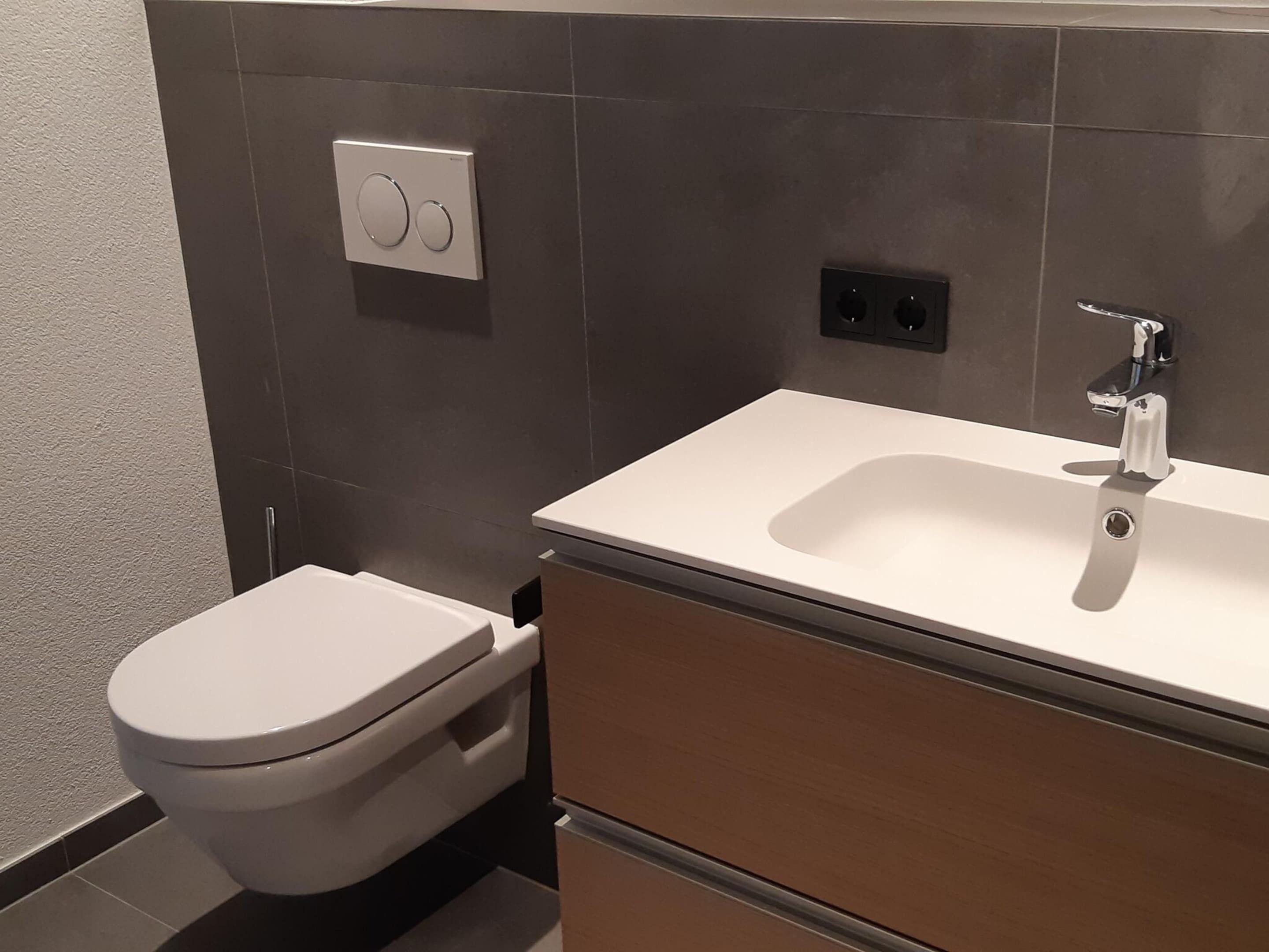 A modern bathroom with a toilet, a sink, and a mirror.