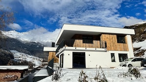 Una casa moderna de dos pisos con techo plano, ventanas amplias y fachada de madera.