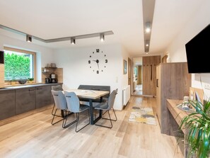 Une cuisine moderne avec un coin repas, des meubles en bois et une grande horloge au mur.