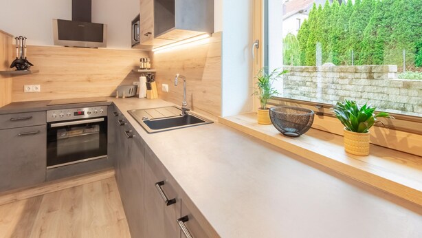 A modern kitchen with a built-in oven, a sink, and a window overlooking a garden. - Apartment in Umhausen With Garden and Barbecue (Umhausen)