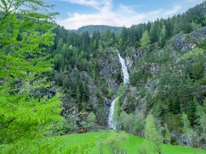 A lush green landscape with a waterfall cascading down a rocky cliff surrounded by dense forest. - Apartment in Umhausen With Garden and Barbecue (Umhausen)