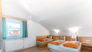A bedroom with two beds, a window with curtains, a radiator, and a wooden floor. - Cosy Apartment in Ladis With Balcony and View (Ladis)