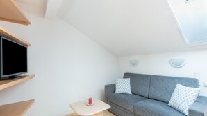 A modern living room with a grey sofa, a small wooden table, a flat-screen TV, and a ceiling light fixture. - Cosy Apartment in Ladis With Balcony and View (Ladis)