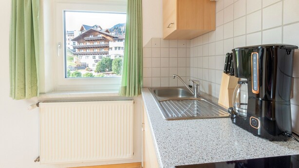 A kitchen with a window, a sink, a coffee maker, and a view of a building outside. - Cosy Apartment in Ladis With Balcony and View (Ladis)