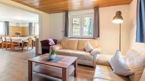 Un salon comprenant une table basse en bois, un canapé, une table à manger avec des chaises et une fenêtre avec des rideaux.