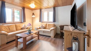 Un salon chaleureux avec deux canapés, une table basse, un téléviseur et un lampadaire.
