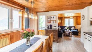 Interior em madeira com sala de jantar, cozinha e sala de estar.