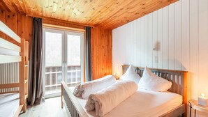 Quarto de madeira com cama, janela e radiador.