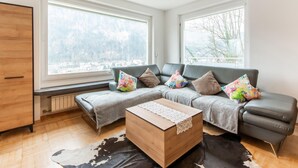 A modern living room with a sectional sofa, a wooden coffee table, and a black and white cowhide rug. - Holiday Home Feldkirch Panoramic Views (Feldkirch)