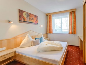 Cozy retreat with a neatly made bed, a painting above, and a window with curtains.