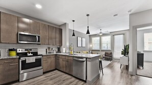 A modern kitchen with stainless steel appliances, wooden cabinets, and a central island. - Elegant 1BR King Suite Close to DT w Fast Wifi (Austin)
