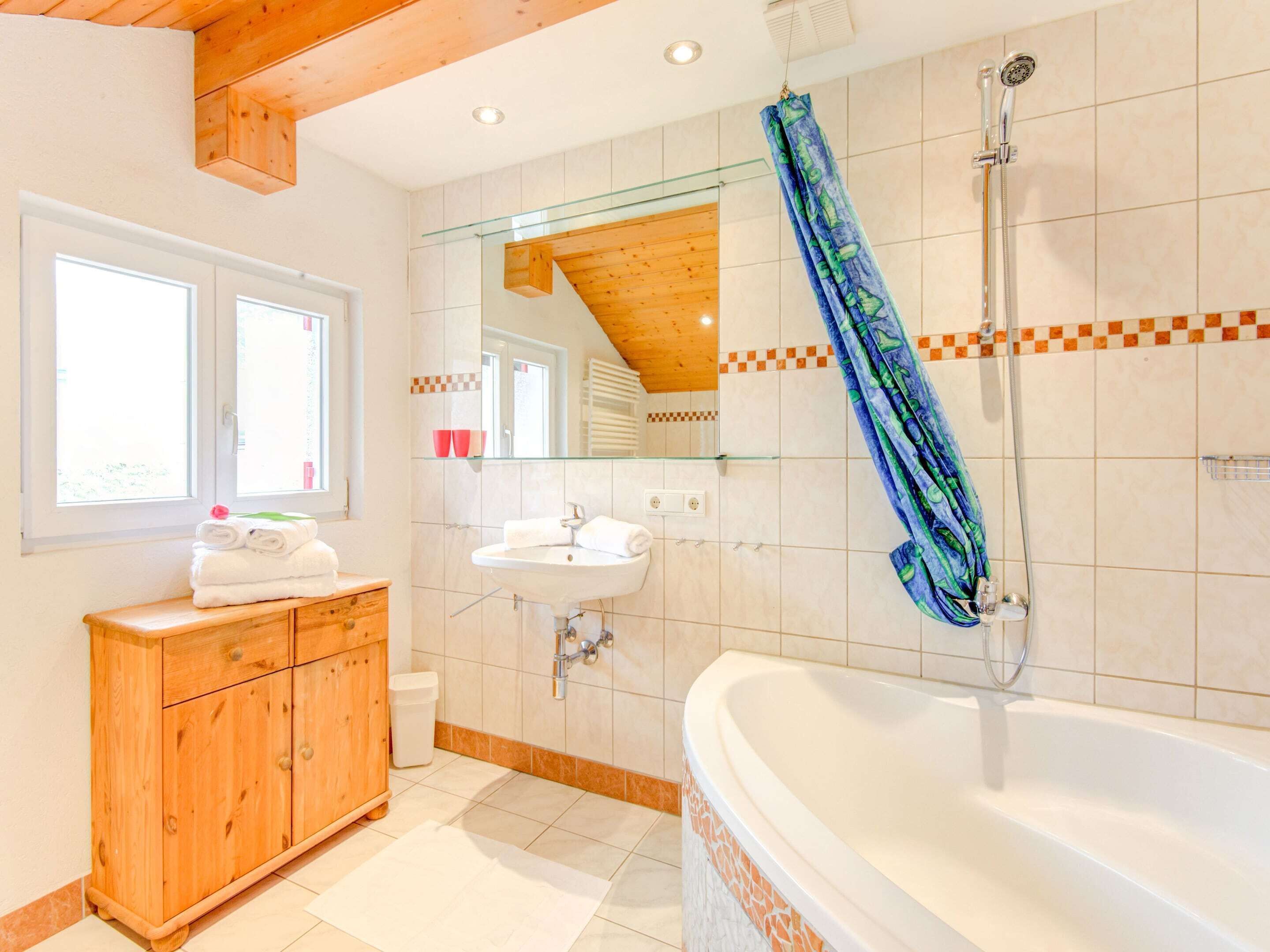 Un baño moderno con tocador de madera, una bañera grande y una ducha.