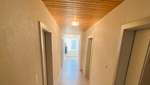 A long, narrow hallway with wooden ceiling beams, light-colored walls, and a wooden floor. - Apartment in Salchau Near Lachtal Ski Area (Oberwölz)