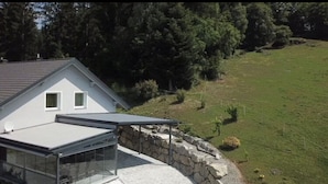 A house with a glass-enclosed patio, a stone wall, and a grassy yard. - Apartment in Salchau Near Lachtal Ski Area (Oberwölz)
