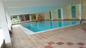 An indoor swimming pool with tiled flooring and yellow chairs along the wall. - Apartment Tauplitz Near Ski Lift & Slopes (Bad Mitterndorf)