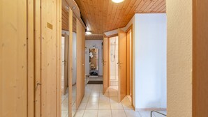 A hallway with wooden doors and a tiled floor, leading to a bathroom with a shower and a toilet. - Apartment Tauplitz Near Ski Lift & Slopes (Bad Mitterndorf)