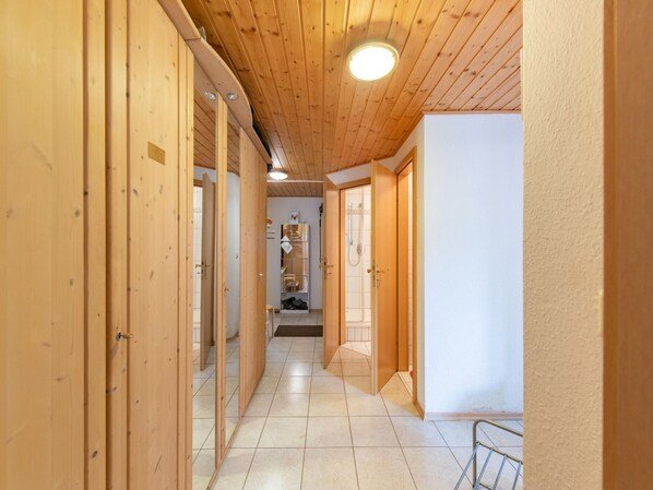 A hallway with wooden doors and a tiled floor, leading to a bathroom with a shower and a toilet. - Apartment Tauplitz Near Ski Lift & Slopes (Bad Mitterndorf)