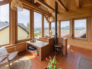 A wooden interior with large windows, a brick fireplace, and a cozy seating area. - Apartment in Kuhnsdorf Near Ski Slopes (Eberndorf)