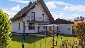 Una casa con un balcone, un'altalena e un prato curato.