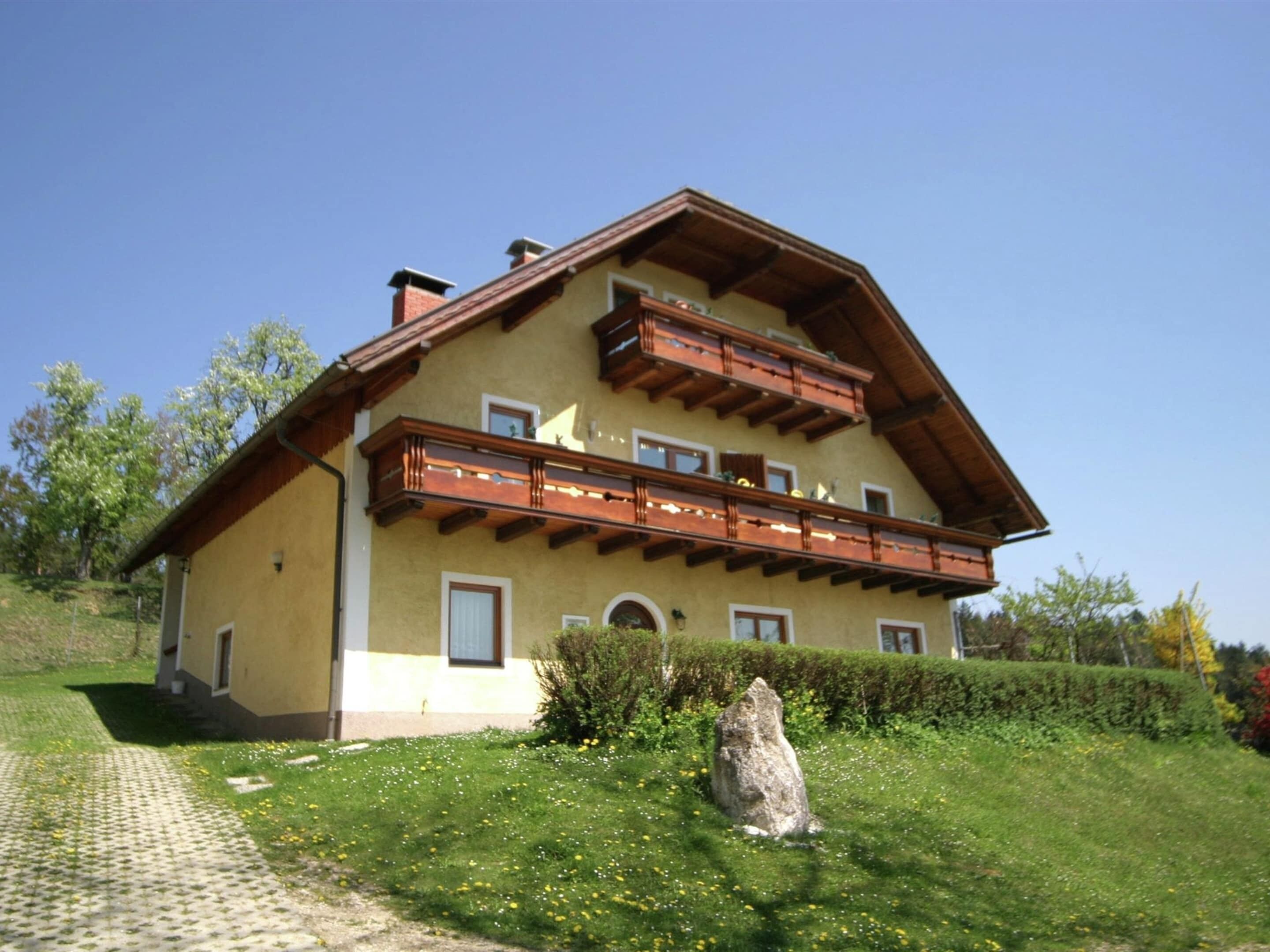 Une maison à deux étages avec un balcon, une allée pavée et une pelouse bien entretenue.