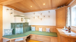 A wooden cabin interior with a green cushioned bench, wooden cabinets, and mounted animal skulls on the wall. - Farmhouse in Hochfilzen With Mountain View (Hochfilzen)