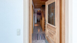 A wooden door with glass panels and a nameplate, a hallway with wooden flooring, and a light switch on the wall. - Farmhouse in Hochfilzen With Mountain View (Hochfilzen)
