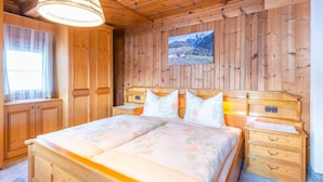 A wooden-paneled bedroom with a bed, bedside tables, and a hanging lamp. - Farmhouse in Hochfilzen With Mountain View (Hochfilzen)