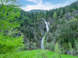 A waterfall cascading down a rocky cliff surrounded by dense forest. - Well-kept Apartment in a Central Location (Umhausen)