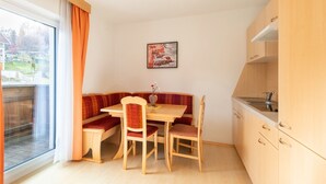 A cozy dining area with a wooden table and chairs, a bench, and a view of the outdoors through a large window. - Inviting Holiday Apartment in Ladis With Balcony (Ladis)