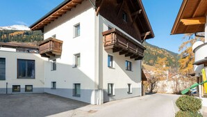 A modern building with a sloped roof, wooden balconies, and a mountain backdrop. - Inviting Holiday Apartment in Ladis With Balcony (Ladis)
