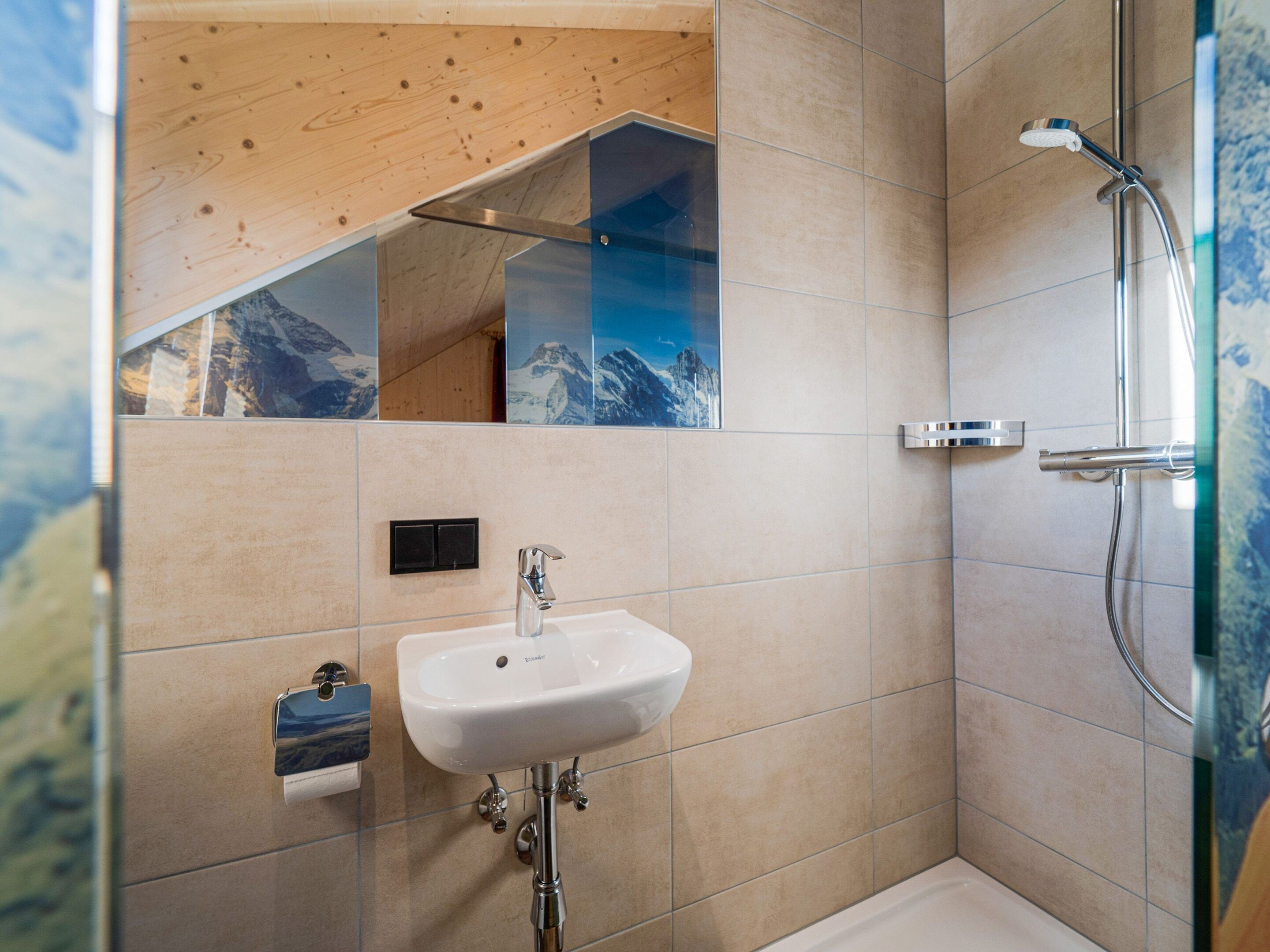 Un baño moderno con ducha, lavabo y espejo.