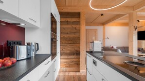 A modern kitchen with white cabinets, stainless steel appliances, and a wooden floor. - Chalet in Hohentauern Near Ski Lift (Hohentauern)