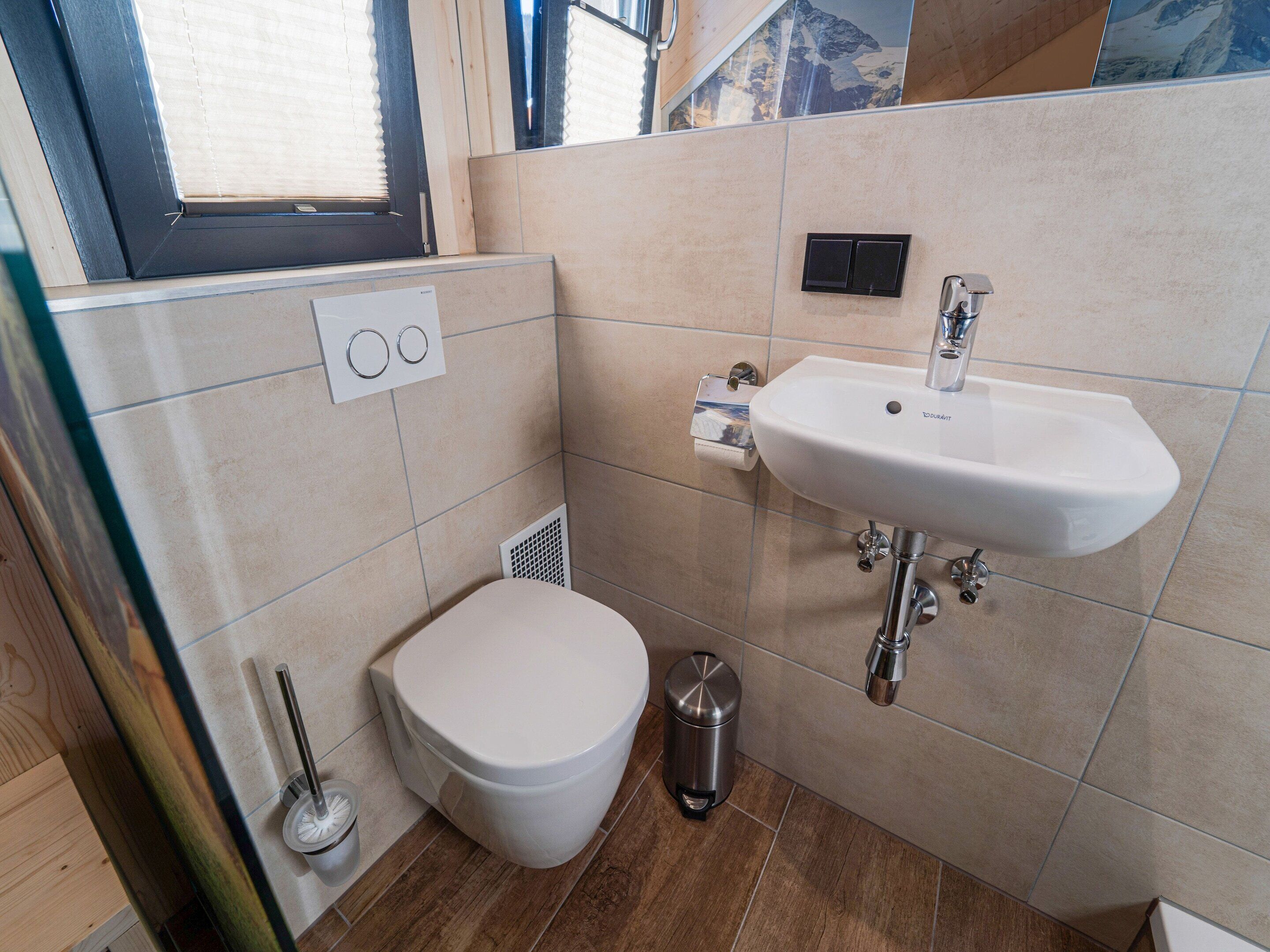 Un baño con inodoro, lavabo y ventana.