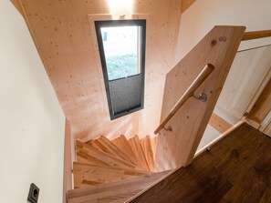 Eine Holztreppe mit einem kleinen Fenster am oberen Ende, einer Handlauf und einem Holzboden.