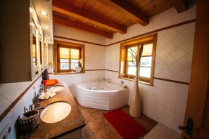 A bathroom with a large bathtub, two sinks, and a mirror.