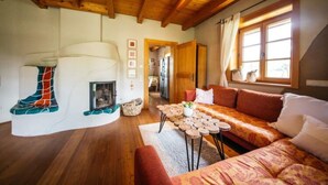 Ein gemütliches Wohnzimmer mit Kamin, Holzbalken, einer Couch und einem Esstisch.