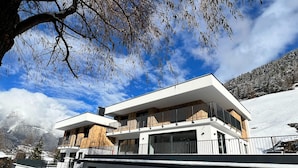 A modern two-story building with a flat roof and large windows, surrounded by snow-covered ground and a clear sky. - Apartment in Solden Near Ski Lift (Soelden)