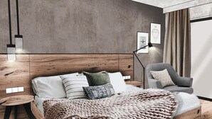 A modern bedroom with a wooden headboard, a large bed with multiple pillows, a side table, a chair, and a floor lamp. - Apartment in Solden Near Ski Lift (Soelden)