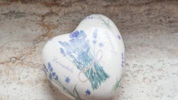 Ein herzförmiges Dekorationsobjekt mit floralen Mustern und Schrift auf einer strukturierten Oberfläche.