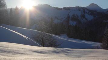 Schneebedeckte Landschaft mit einem Berg im Hintergrund und der Sonne, die scheint.